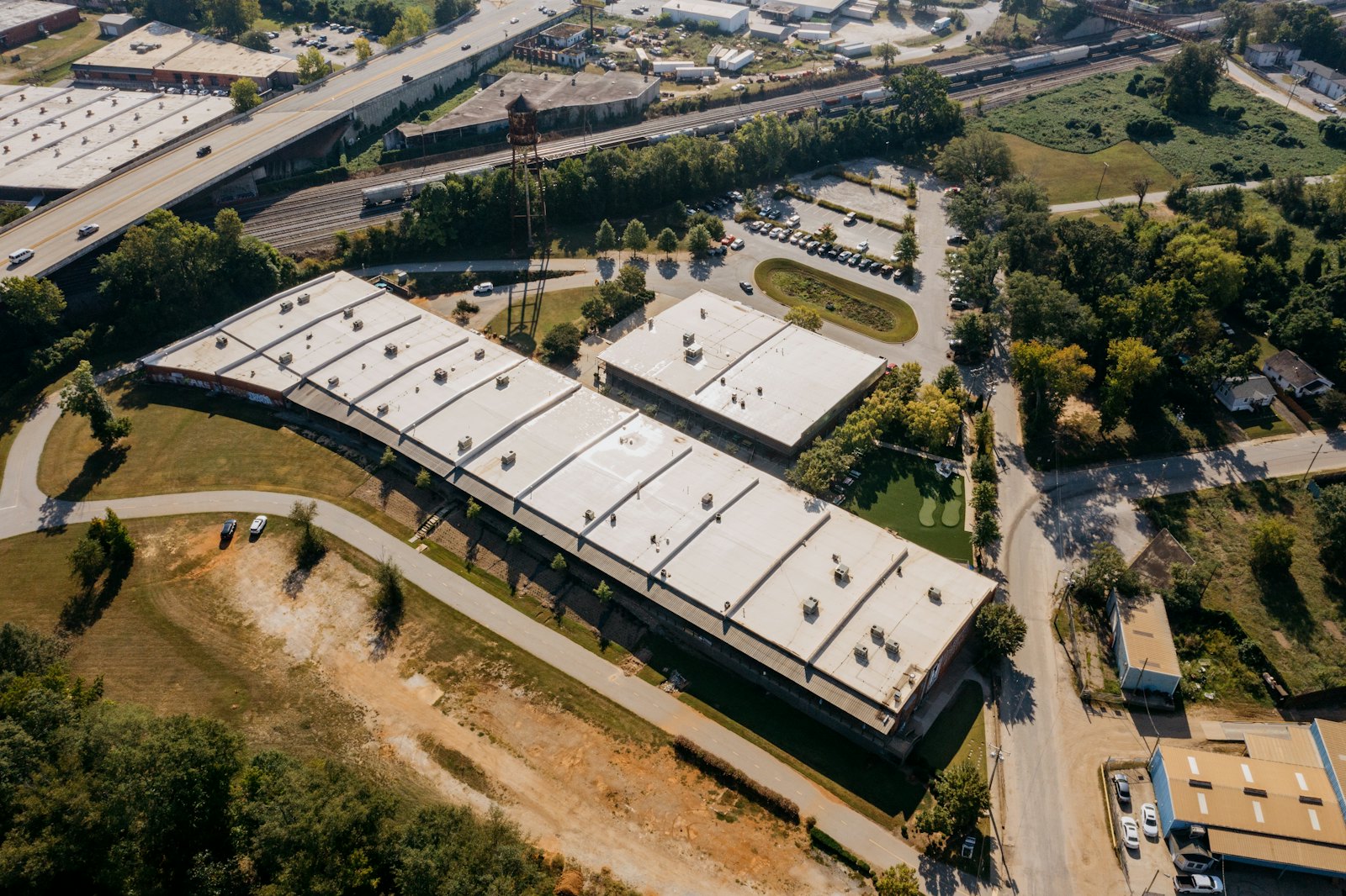 Commercial building roof photographed from above, showing rooftop mechanical units and an adjoining parking lot.