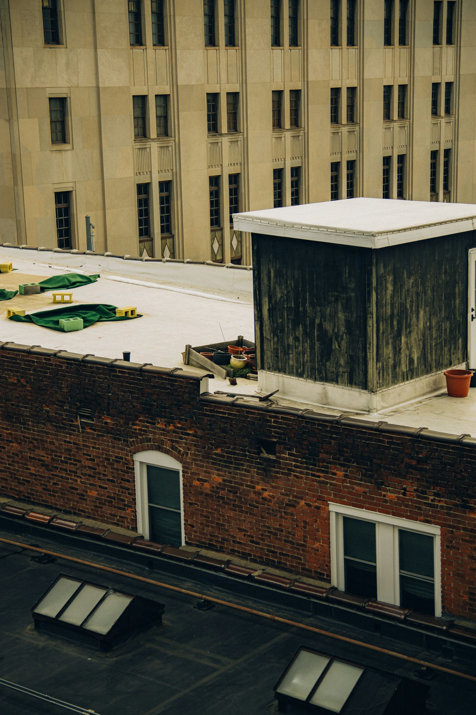 White coated low-slope roof on an older commercial building, with a clad stair bulkhead, parapet coping and a darker adjoining roof carrying skylights.
